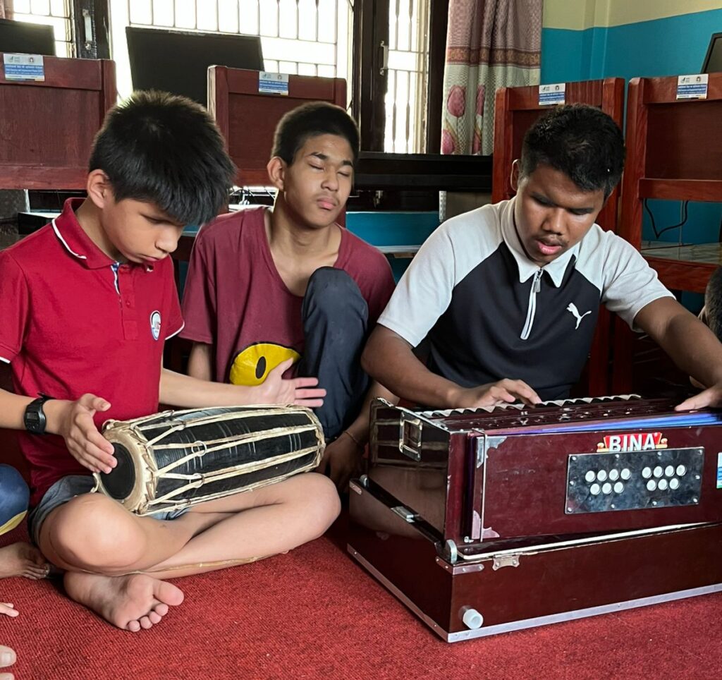3 kids sitting on the floor and playing musical instruments.
